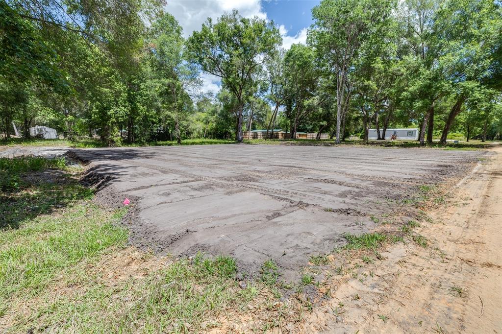 A cleared, level dirt lot is surrounded by mature trees in a wooded area — SE 124TH AVENUE, WEBSTER, FL