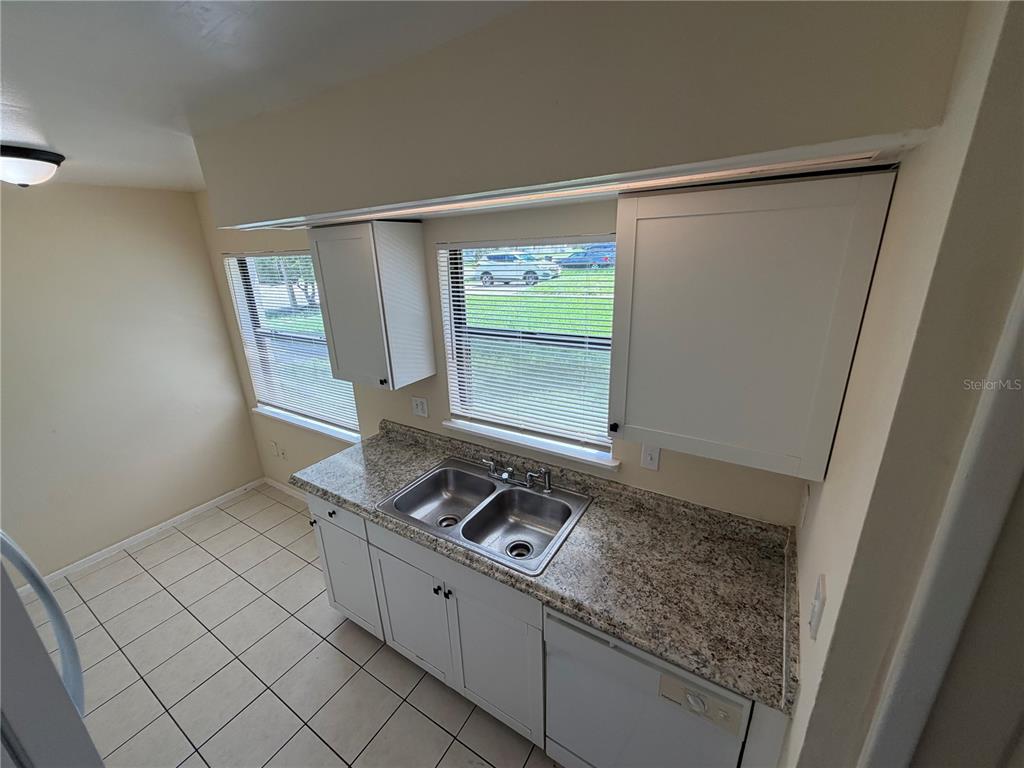 A kitchen featuring white cabinets, granite-look countertops, white appliances, and light-colored tile flooring — 11608 ANJALI COURT, ORLANDO, FL