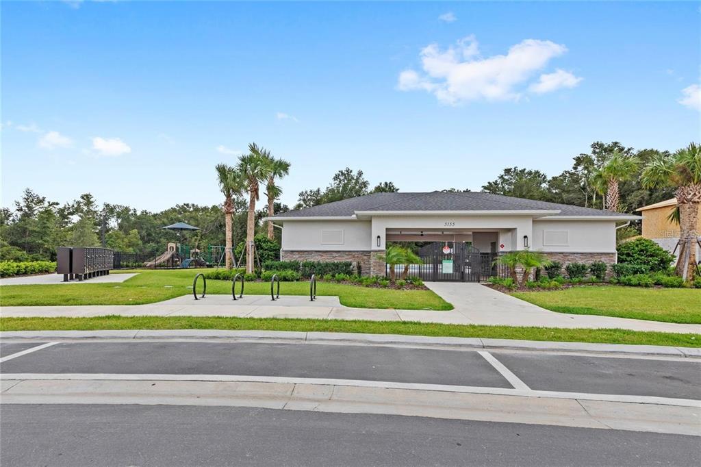 A community clubhouse with a pool entrance, bike racks, and a playground in the background — 5937 STONEYBROOK HILLS PARKWAY, MOUNT DORA, FL