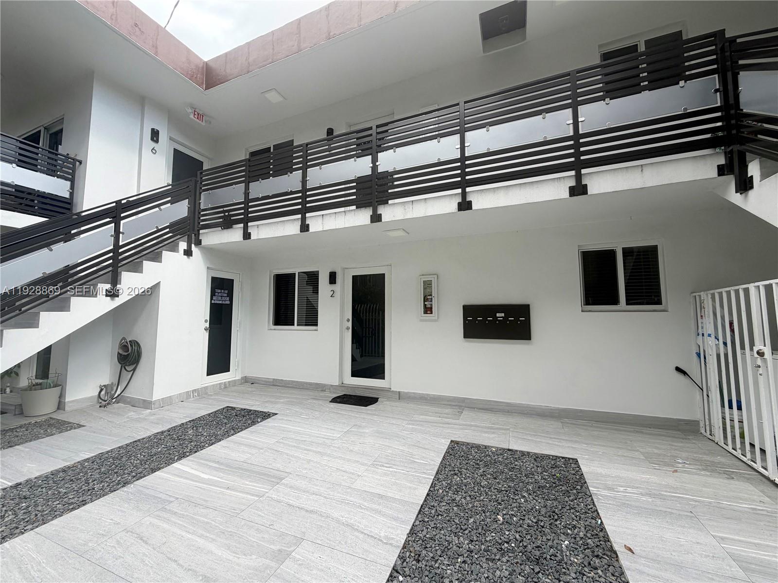 A two-story building exterior features white walls, a metal staircase, and a tiled courtyard — 1629 SW 3rd St # 5, Miami FL 33135, MIAMI, FL