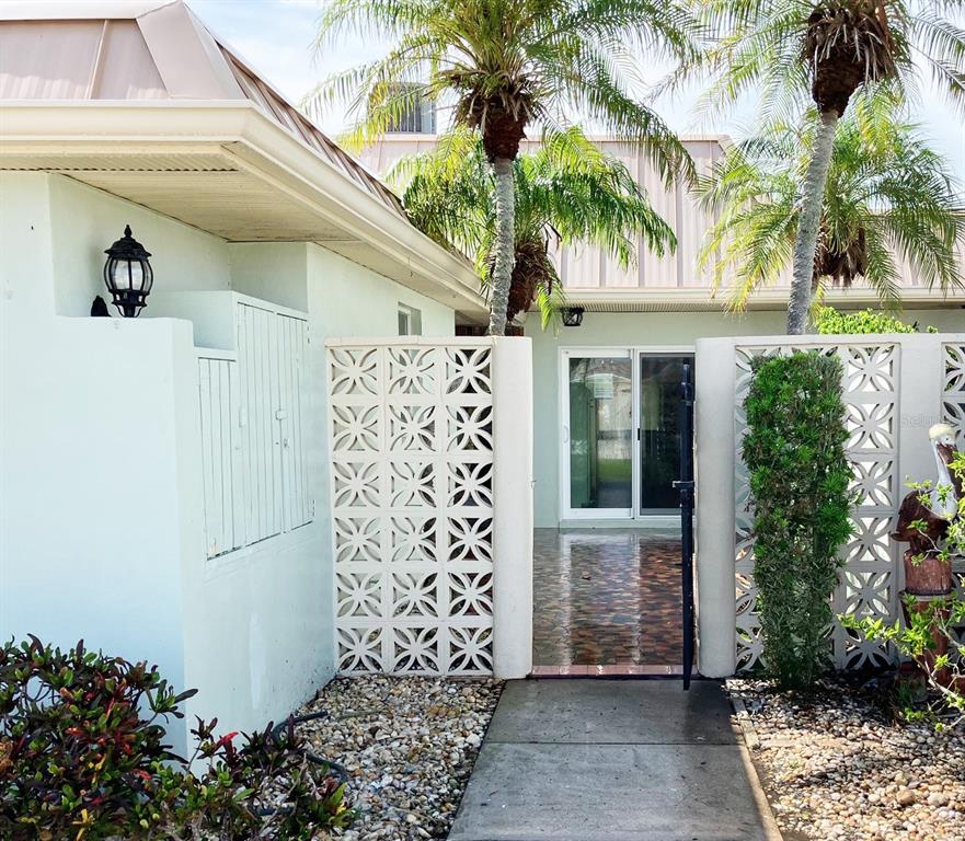A paved walkway leads to a patio entrance framed by decorative white breeze block walls — 628 BOCA CIEGA POINT BOULEVARD S, ST PETERSBURG, FL