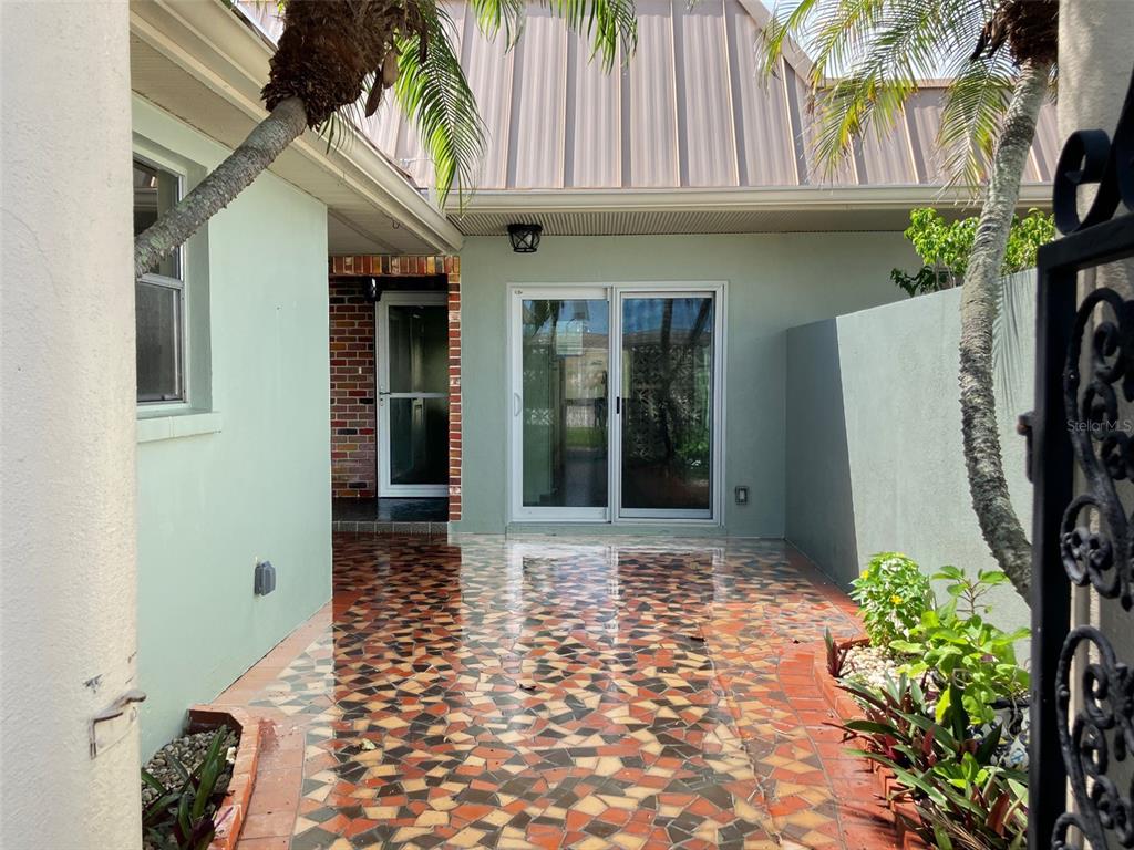 A paved courtyard with a mosaic tile floor sits between a house and a privacy wall — 628 BOCA CIEGA POINT BOULEVARD S, ST PETERSBURG, FL