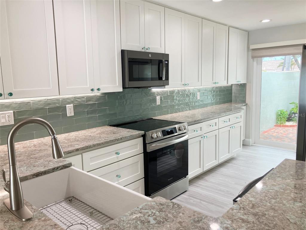 A kitchen features white cabinets, a green subway tile backsplash, and granite countertops — 628 BOCA CIEGA POINT BOULEVARD S, ST PETERSBURG, FL