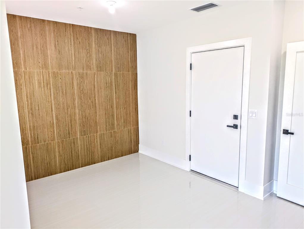 A room with light-colored tile flooring, white walls, and a wood-slatted accent wall — 2194 FRUITVILLE ROAD, SARASOTA, FL