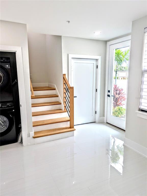 A bright entryway features white tile floors, a wooden staircase, and a glass-paned exterior door — 2194 FRUITVILLE ROAD, SARASOTA, FL