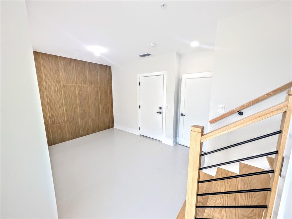 An entryway features light tile flooring, a wood-paneled accent wall, and a wooden staircase — 2194 FRUITVILLE ROAD, SARASOTA, FL