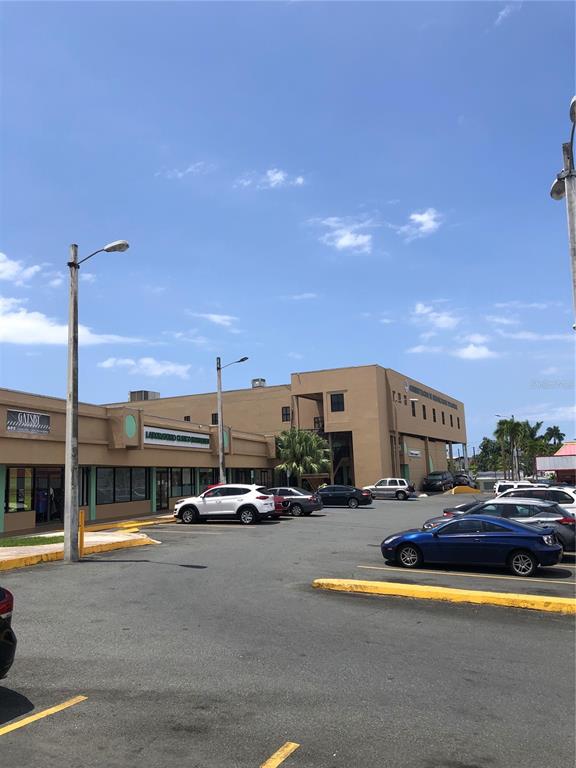 A parking lot sits in front of a tan commercial building under a blue sky — 167 N RAMON L RIVERA, KM 21,3,FOREST HILLS PLAZA AVENUE N UNIT 2, BAYAMON, PR