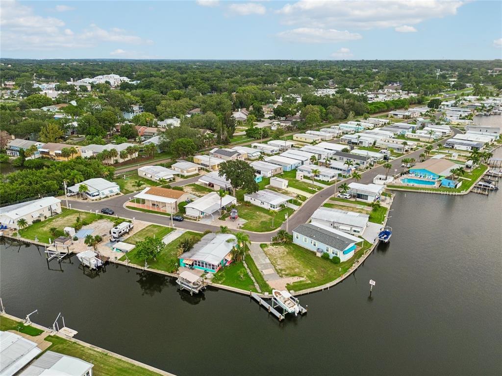 An aerial view shows a waterfront mobile home community with docks and a swimming pool — 102 SCHOONER DRIVE UNIT 102, PALM HARBOR, FL
