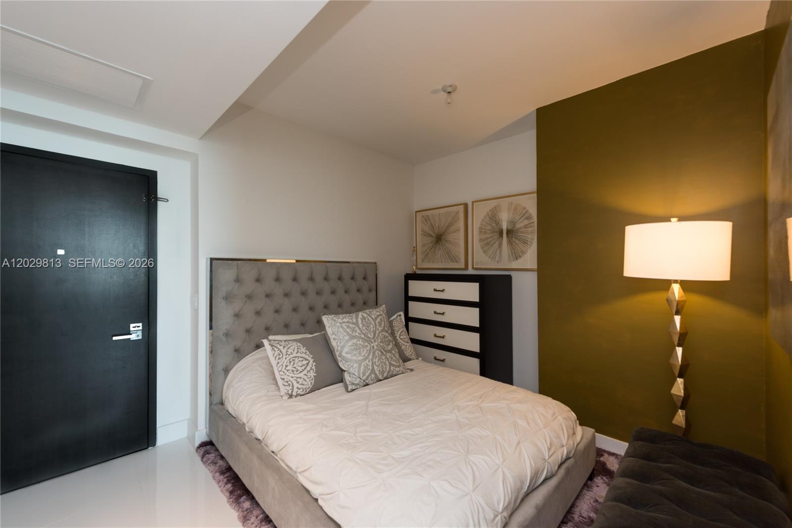 A bedroom features a tufted gray bed, a black dresser, and an olive green wall — 1080 Brickell Ave # 4105, Miami FL 33131, MIAMI, FL