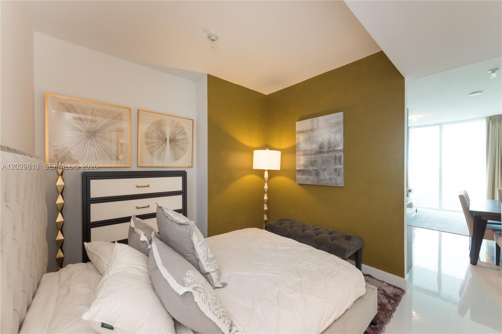 A bedroom features a white bed, a dark dresser, and an olive green accent wall — 1080 Brickell Ave # 4105, Miami FL 33131, MIAMI, FL