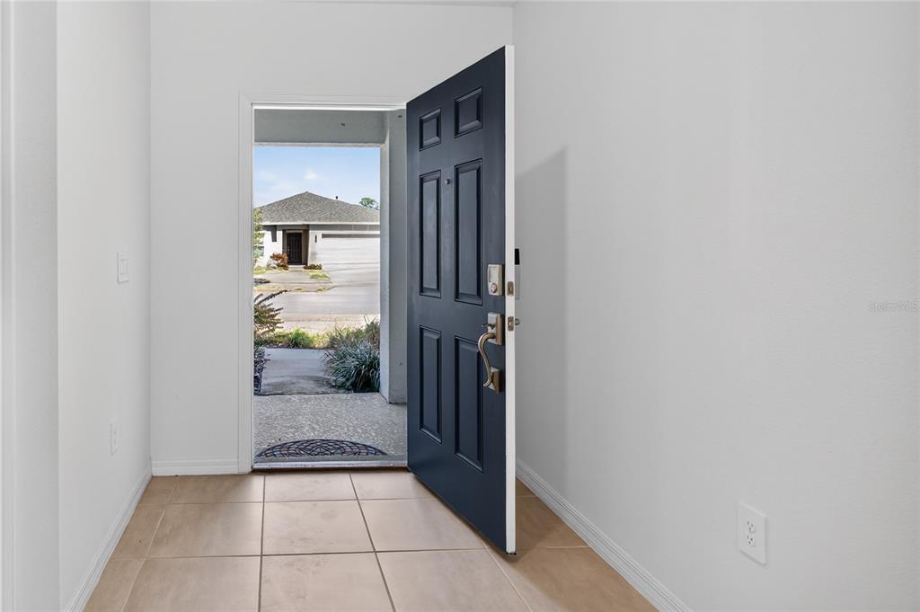 An open dark blue front door reveals a view of a suburban street and house — 9633 RAMPART ROAD, LEESBURG, FL