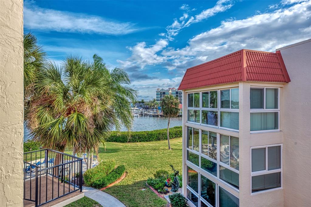 An exterior view of a multi-story building with a red roof overlooking a waterfront area — 260 SANTA MARIA STREET UNIT 311, VENICE, FL