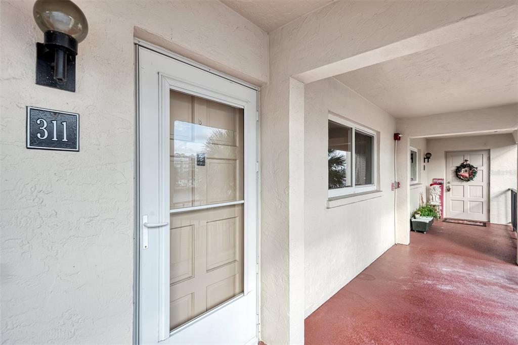 An exterior view shows the entrance to unit 311 with a storm door and walkway — 260 SANTA MARIA STREET UNIT 311, VENICE, FL