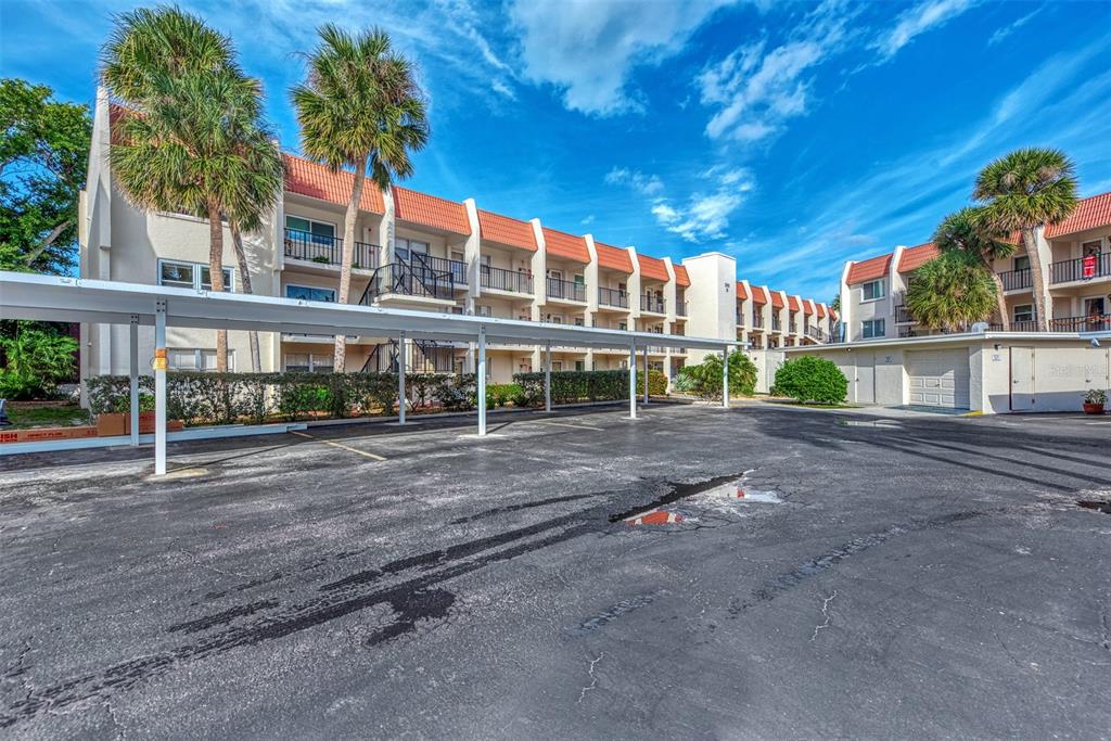 An exterior view of an apartment building with a covered parking area and palm trees — 260 SANTA MARIA STREET UNIT 311, VENICE, FL