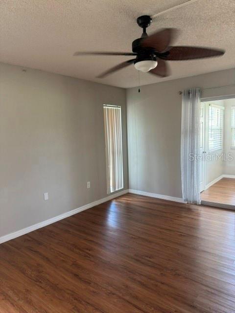 An empty room features wood-look flooring, a ceiling fan, and a sliding glass door — 4743 JASPER DRIVE UNIT 101, NEW PORT RICHEY, FL