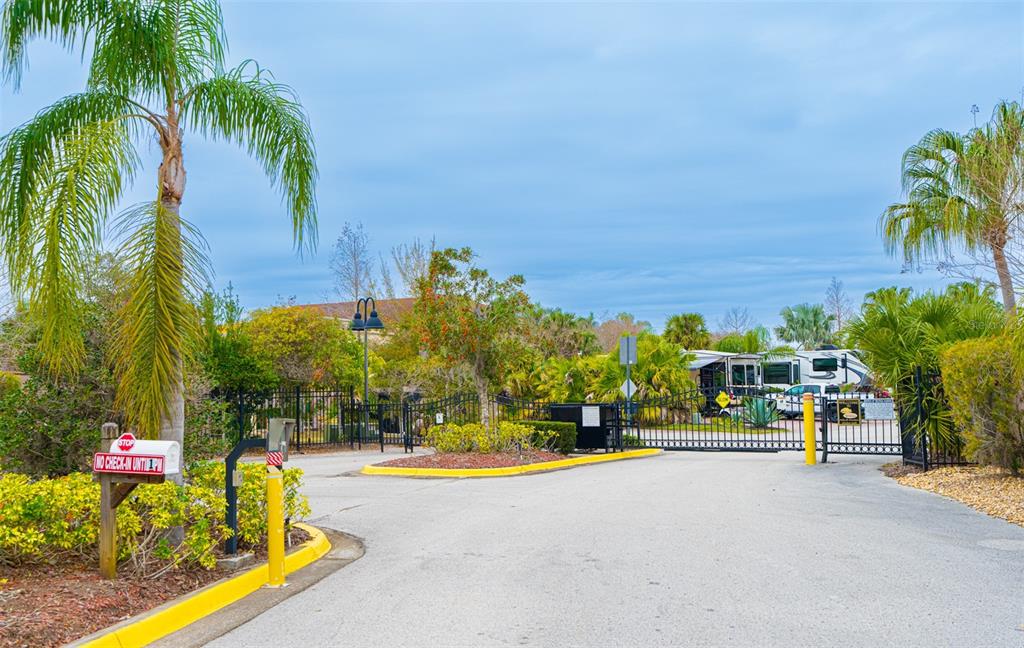 A gated entrance with a palm tree, a stop sign, and a recreational vehicle visible — 6770 AMANDA VISTA CIRCLE, LAND O LAKES, FL