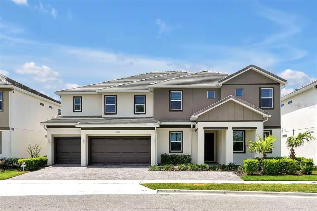 A two-story suburban house with a three-car garage, gray roof, and tan and brown exterior — 3860 SONOMA BOULEVARD, KISSIMMEE, FL
