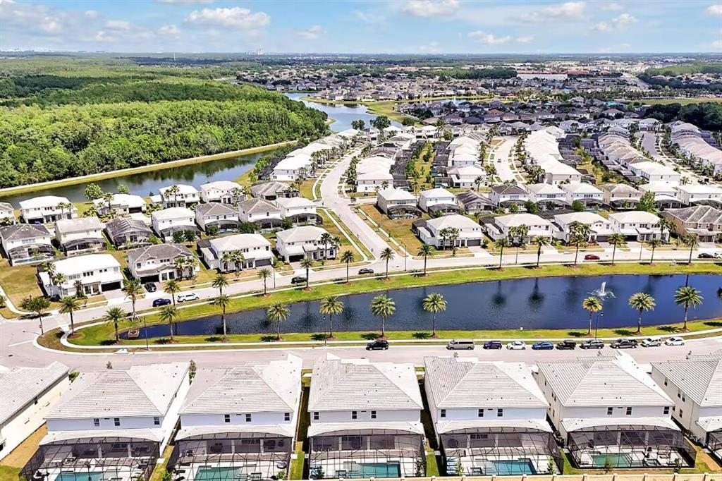 An aerial view of a suburban neighborhood featuring houses with pools and a central pond — 3860 SONOMA BOULEVARD, KISSIMMEE, FL