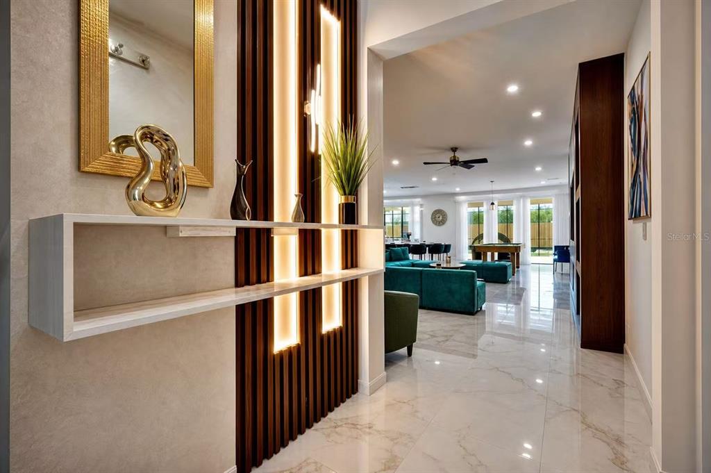 A modern entryway features a floating shelf, vertical wood slats with lighting, and marble flooring — 3860 SONOMA BOULEVARD, KISSIMMEE, FL