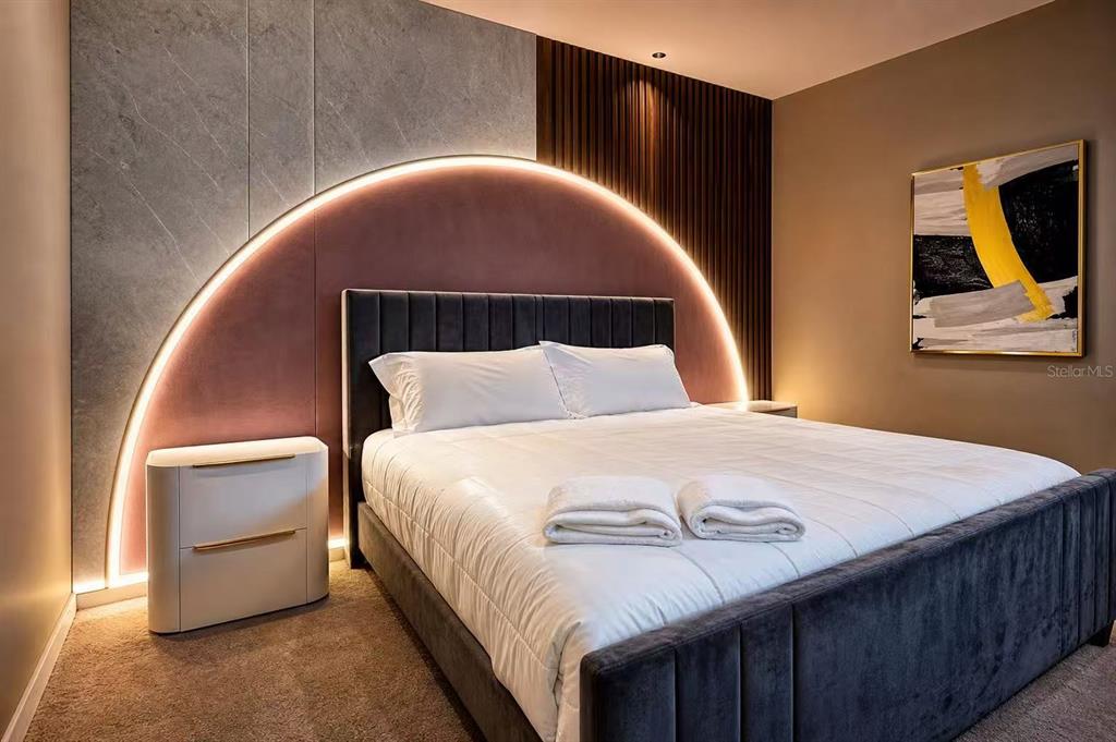A bedroom features a dark upholstered bed against a wall with a backlit circular headboard design — 3860 SONOMA BOULEVARD, KISSIMMEE, FL