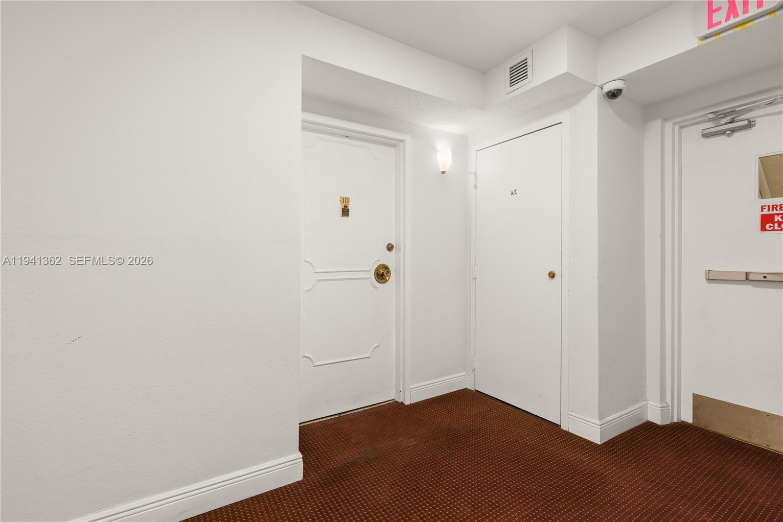A hallway features a white apartment door, an A/C closet door, and a fire exit door — 437 Golden Isles Dr # 4D, Hallandale Beach FL 33009, HALLANDALE BEACH, FL