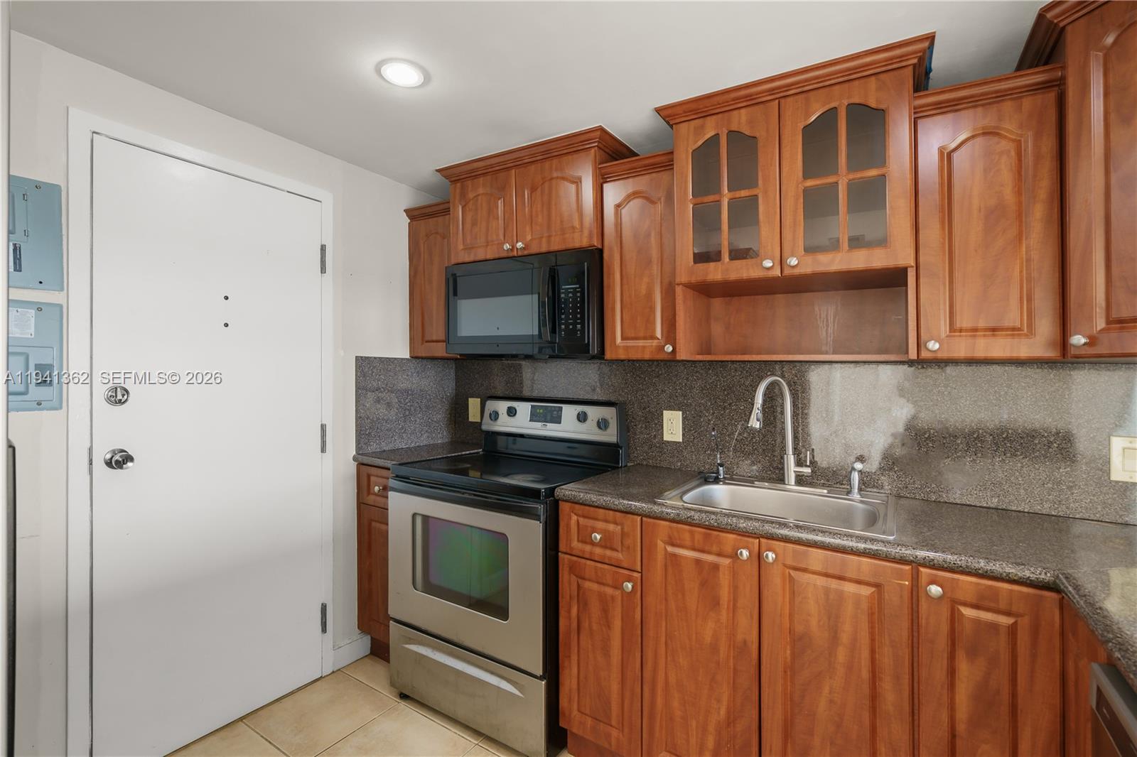 A kitchen features wood cabinets, stainless steel appliances, and a dark granite countertop — 437 Golden Isles Dr # 4D, Hallandale Beach FL 33009, HALLANDALE BEACH, FL