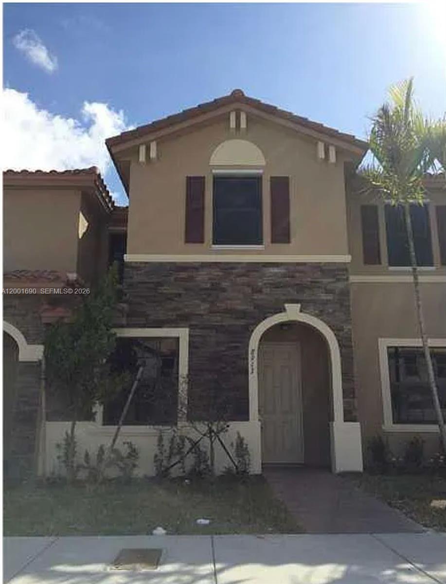 A two-story townhouse exterior features a stone-veneer facade, arched entryway, and brown window shutters — 8913 W 35th Way, Hialeah FL 33018, HIALEAH, FL