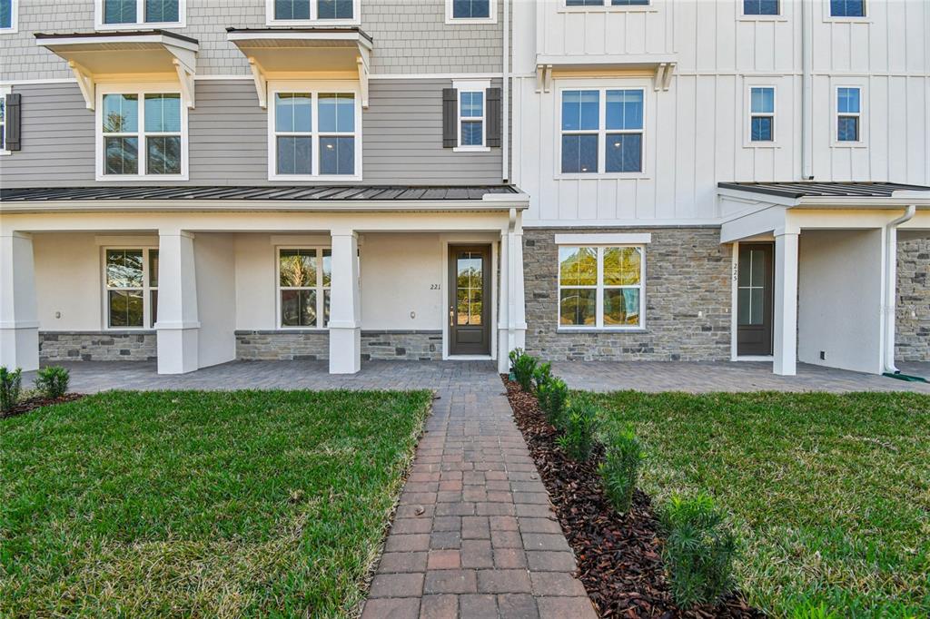 A multi-story townhouse exterior features a stone base, gray and white siding, and paved walkways — 221 PASQUALA UNIT 18, OVIEDO, FL