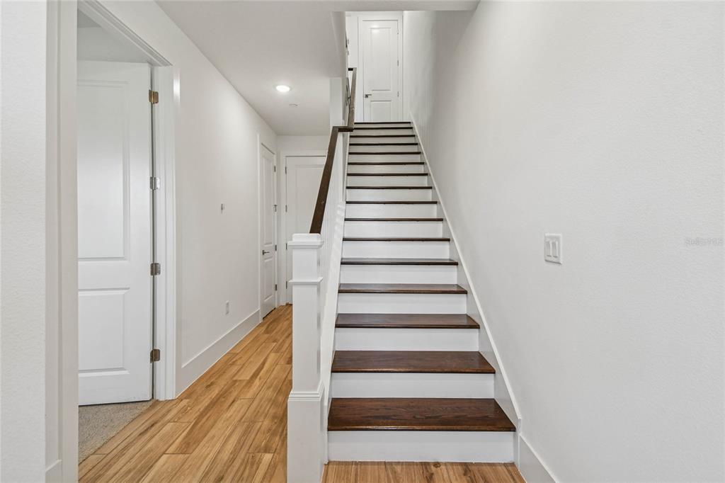 A staircase with dark wood treads and white risers leads to a landing with a door — 221 PASQUALA UNIT 18, OVIEDO, FL