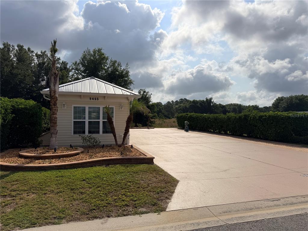 A small, light-colored building with a metal roof sits beside a large concrete driveway — 9465 SE 47TH WAY, WEBSTER, FL