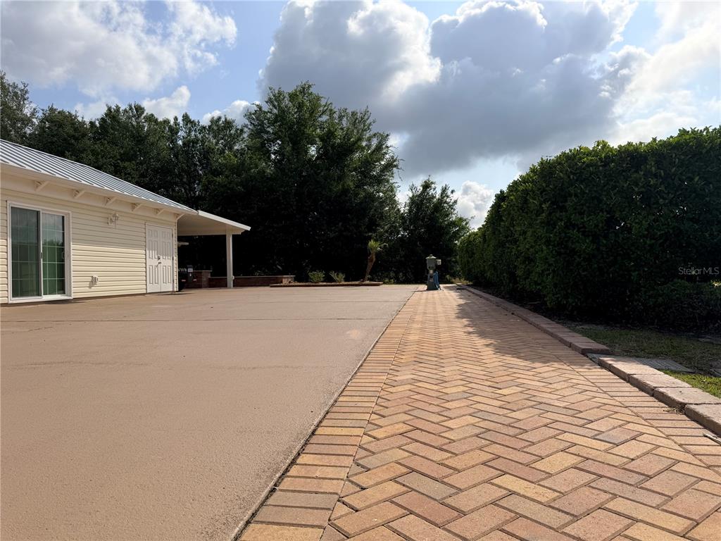 A paved walkway runs alongside a smooth driveway next to a house with light siding — 9465 SE 47TH WAY, WEBSTER, FL