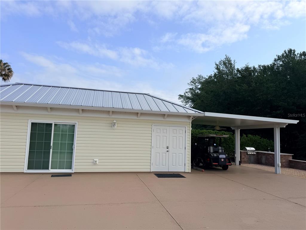 A light yellow house exterior features a metal roof, sliding glass doors, and a carport — 9465 SE 47TH WAY, WEBSTER, FL