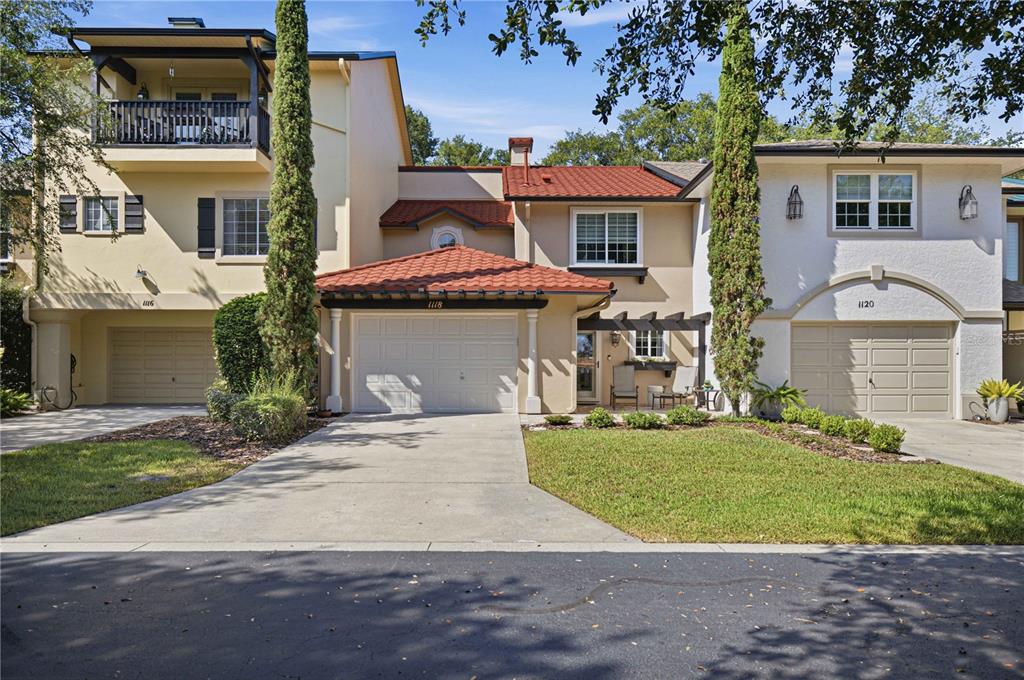 A row of three attached townhomes with stucco exteriors, red tile roofs, and concrete driveways — 1118 AVENIDA DE LAS CASAS, LADY LAKE, FL