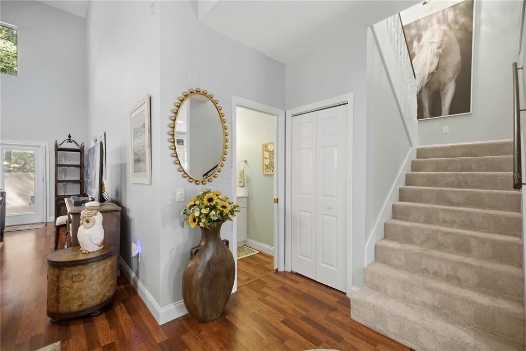 An entryway features a staircase, a mirror, a vase with sunflowers, and hardwood flooring — 1118 AVENIDA DE LAS CASAS, LADY LAKE, FL