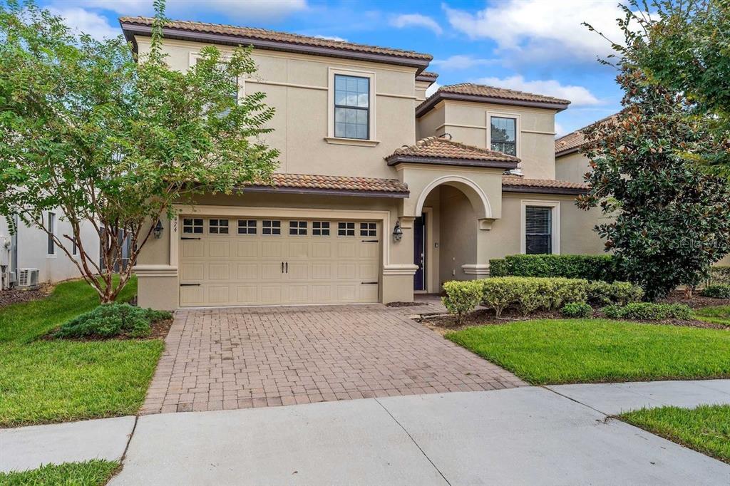 A two-story beige stucco house with a tiled roof and a paved driveway — 1474 ROLLING FAIRWAY DRIVE, DAVENPORT, FL