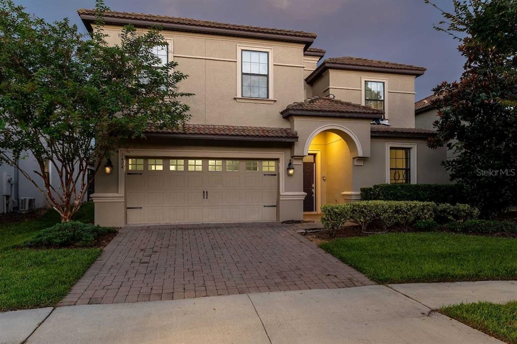A two-story house with a beige stucco exterior, a two-car garage, and a paved driveway — 1474 ROLLING FAIRWAY DRIVE, DAVENPORT, FL