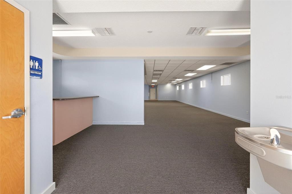 An empty commercial space features a carpeted floor, a small service counter, and a water fountain — 17809 SE 109TH AVENUE, SUMMERFIELD, FL