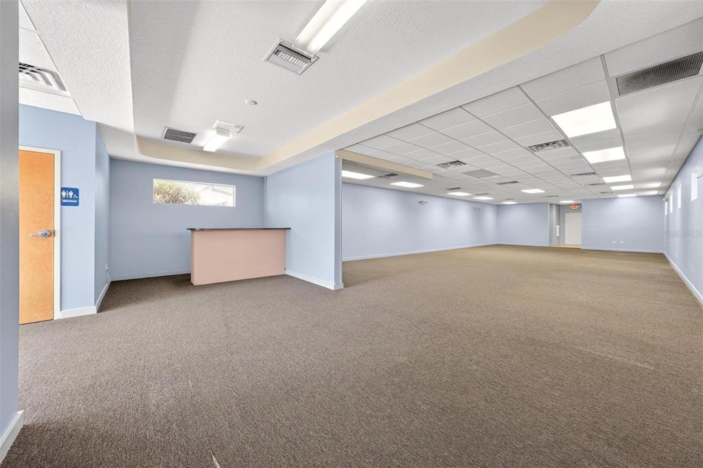 An empty commercial space with light blue walls, brown carpeting, and a drop ceiling — 17809 SE 109TH AVENUE, SUMMERFIELD, FL