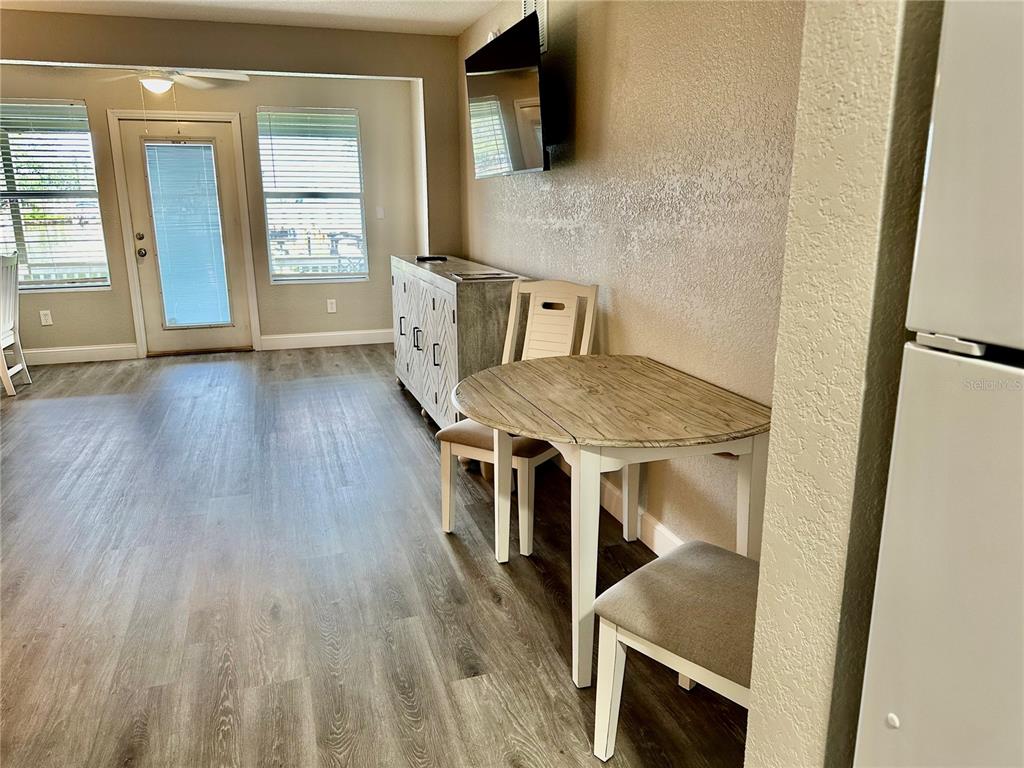 A dining area features a round wooden table, two chairs, and a dresser near a door — 5297 S CHEROKEE WAY UNIT 104, HOMOSASSA, FL