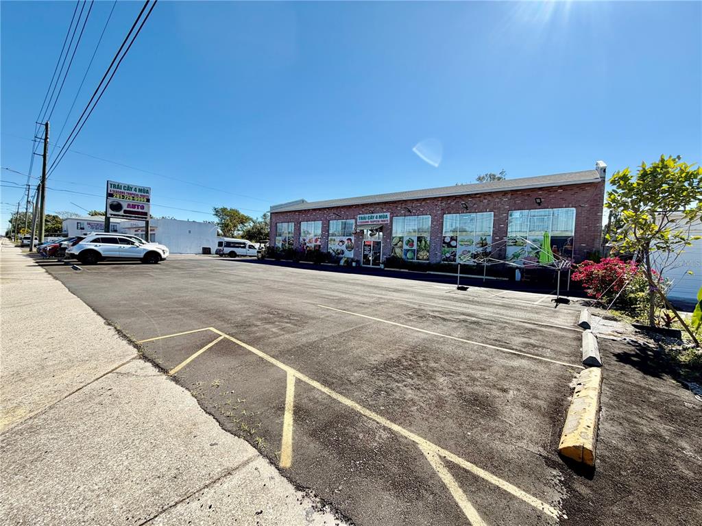 A brick commercial building features a large asphalt parking lot with painted yellow lines — 4022 54TH AVENUE N, ST PETERSBURG, FL