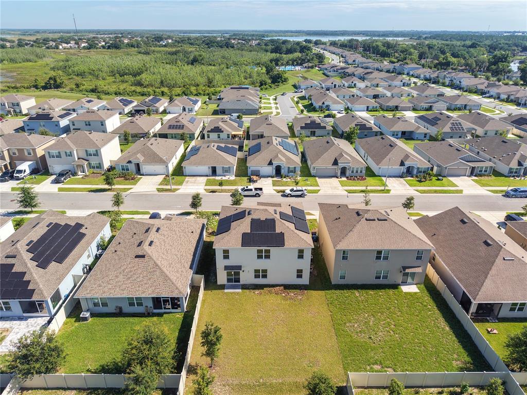 An aerial view shows a suburban neighborhood with houses featuring solar panels and backyards — 4027 ALISSA LANE, HAINES CITY, FL