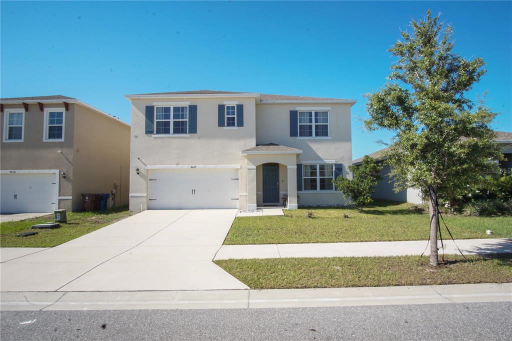 A two-story suburban house with a beige stucco exterior, a two-car garage, and a driveway — 4027 ALISSA LANE, HAINES CITY, FL
