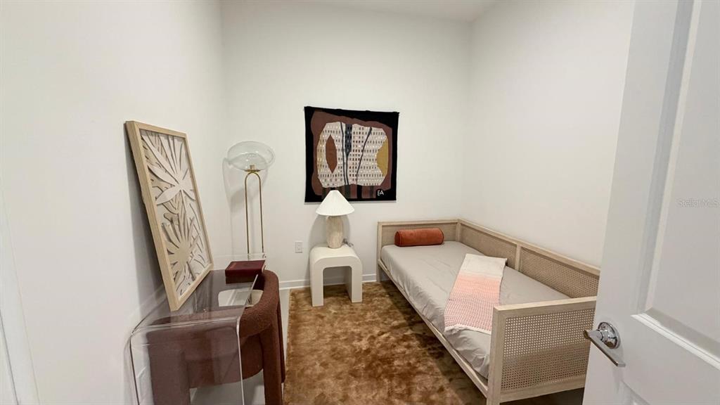 A small bedroom features a daybed, a brown shag rug, and a modern side table — 5587 MILLENIA PARK BLVD UNIT 210, ORLANDO, FL