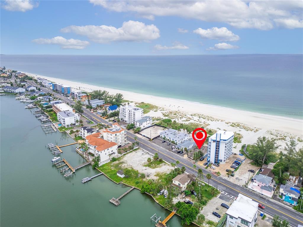 An aerial view shows a coastal road separating a beach from buildings and boat docks — 10178 GULF BOULEVARD, TREASURE ISLAND, FL