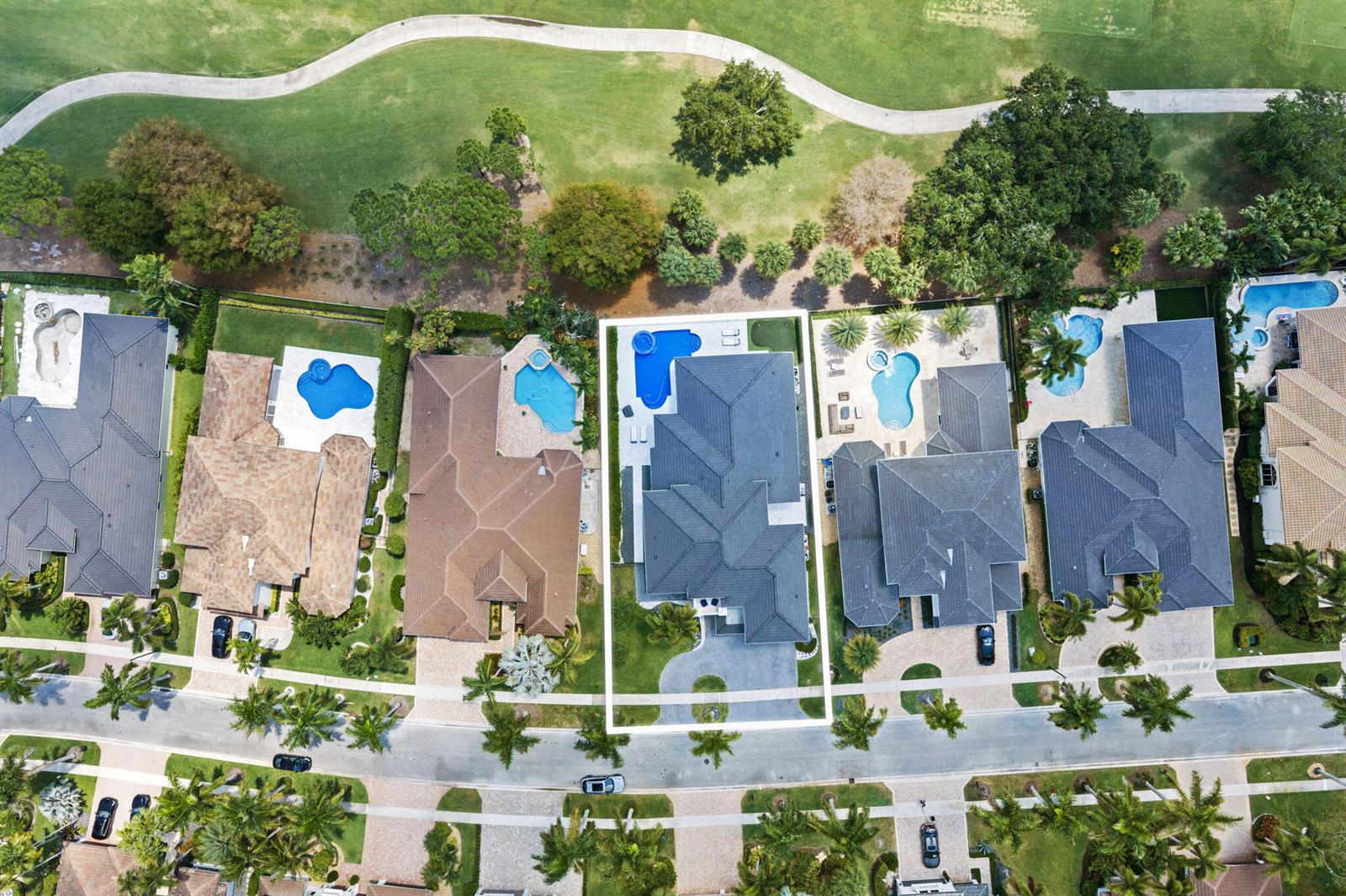 An aerial view shows a residential street with several houses featuring swimming pools and landscaping — 16014 Laurel Creek Drive, Delray Beach FL 33446, DELRAY BEACH, FL