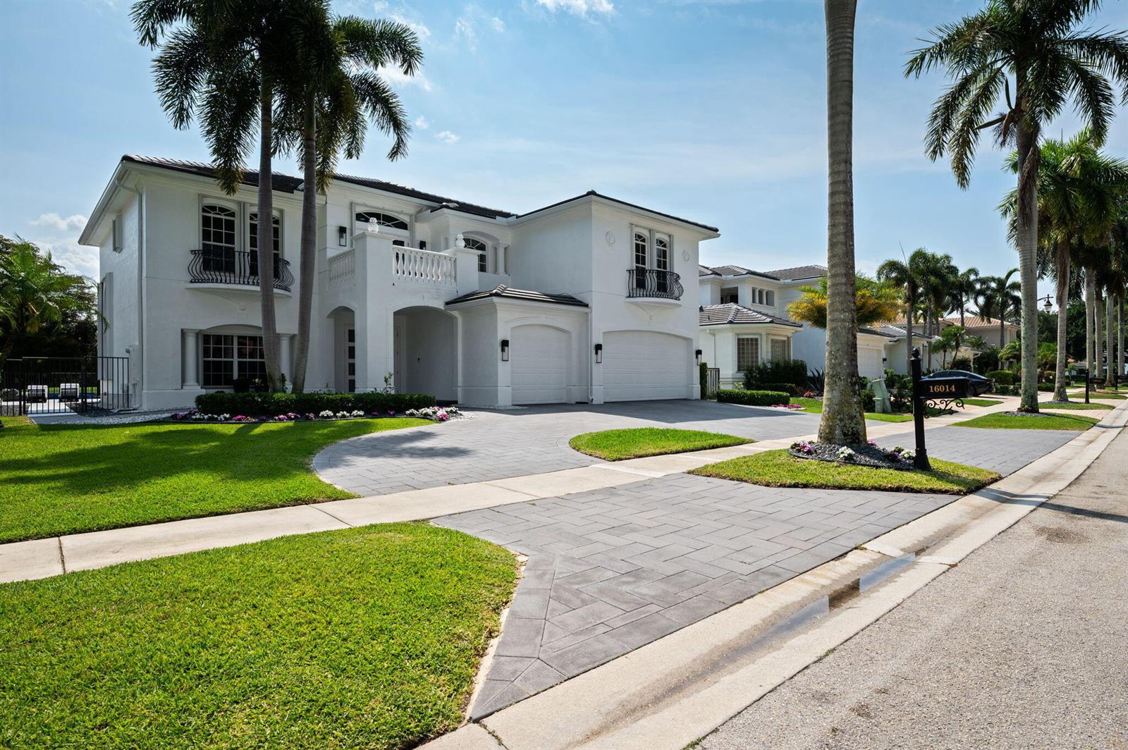 A two-story white house with a paved driveway, palm trees, and a manicured lawn — 16014 Laurel Creek Drive, Delray Beach FL 33446, DELRAY BEACH, FL