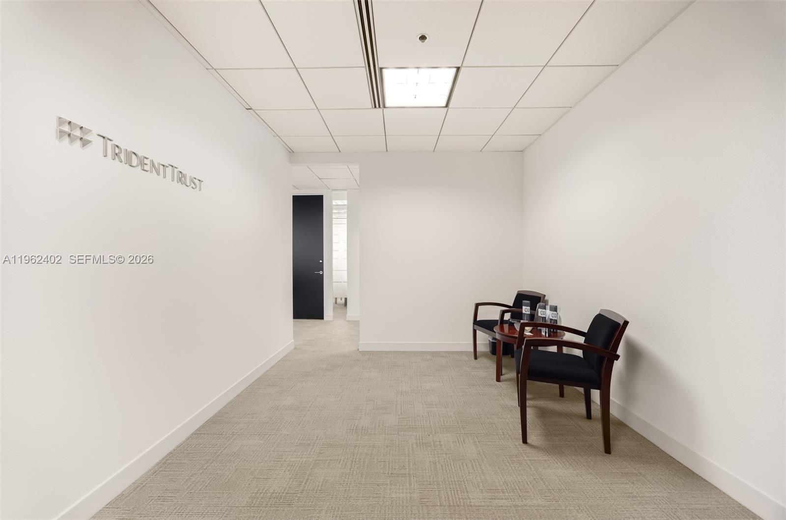 A small office waiting area features a Trident Trust sign, two chairs, and carpeted flooring — 1001 Brickell Bay Dr # 2112, Miami FL 33131, MIAMI, FL