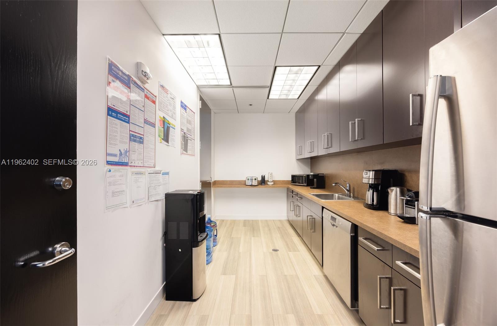 This office breakroom features dark cabinetry, stainless steel appliances, a sink, and light wood flooring — 1001 Brickell Bay Dr # 2112, Miami FL 33131, MIAMI, FL