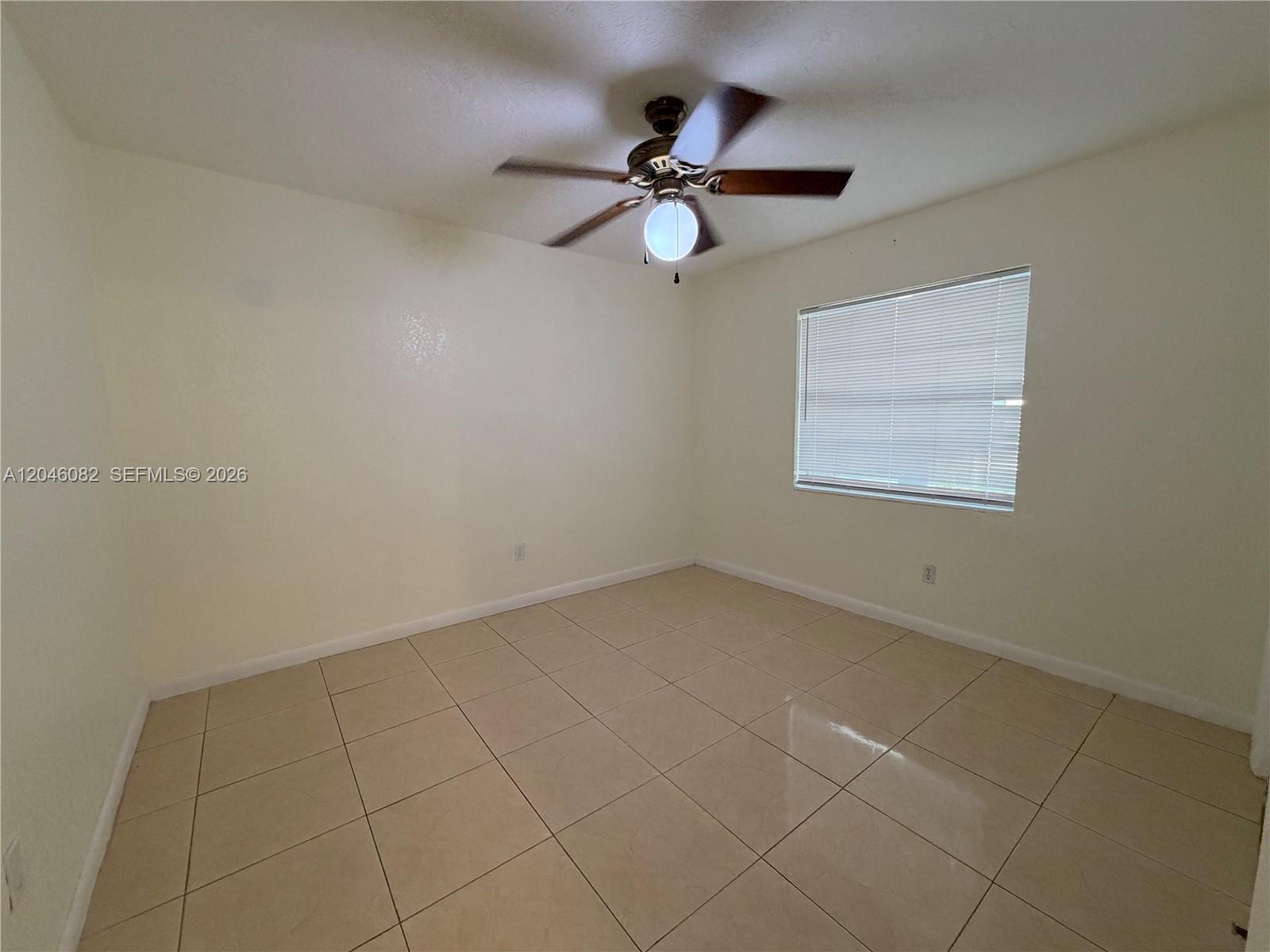 An empty room features beige tile flooring, white walls, and a ceiling fan with light — 5960 NE 5th Ct # 2, Miami FL 33137, MIAMI, FL
