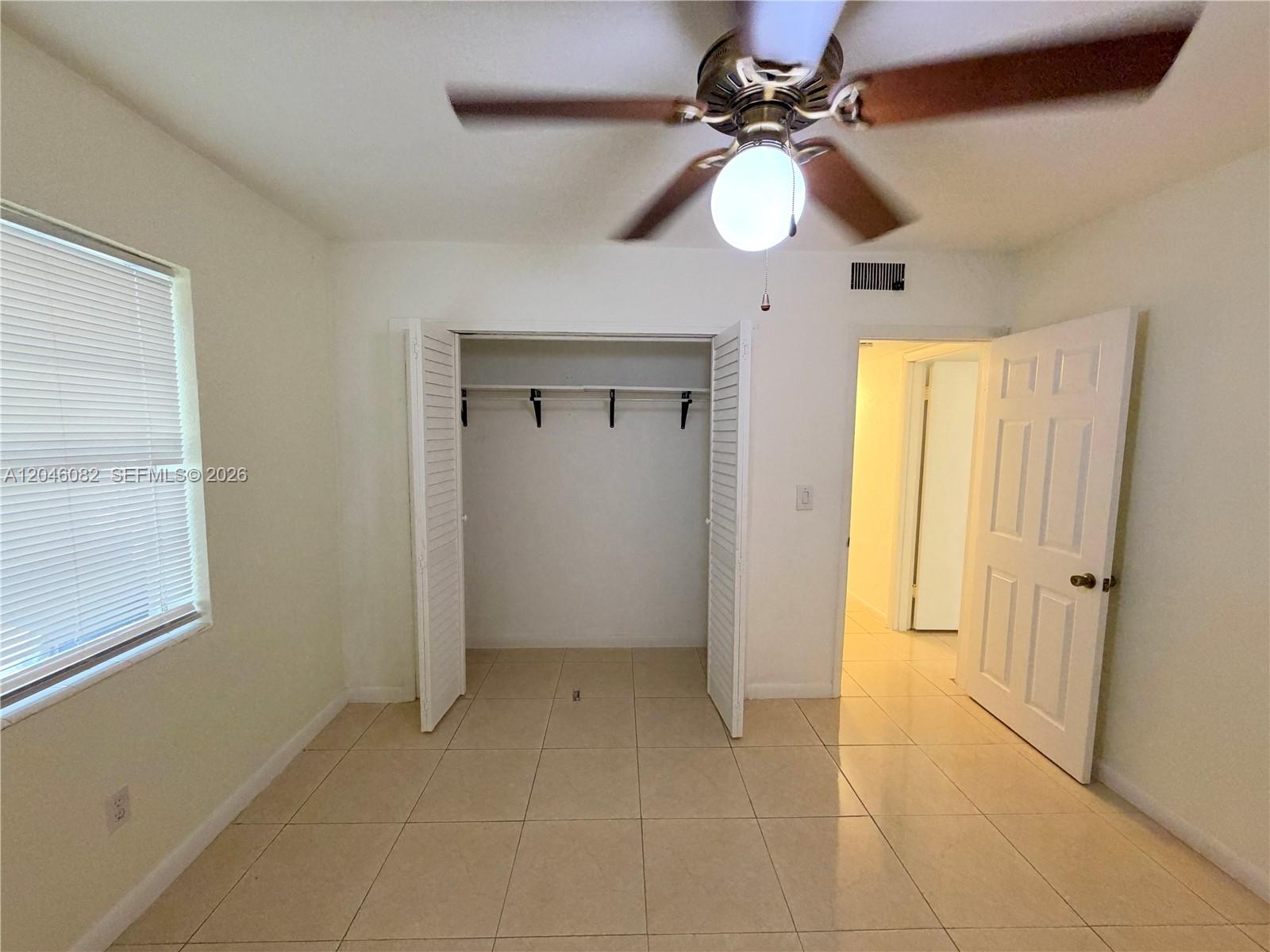 A bedroom features beige tile flooring, a ceiling fan, a closet, and an open doorway — 5960 NE 5th Ct # 2, Miami FL 33137, MIAMI, FL